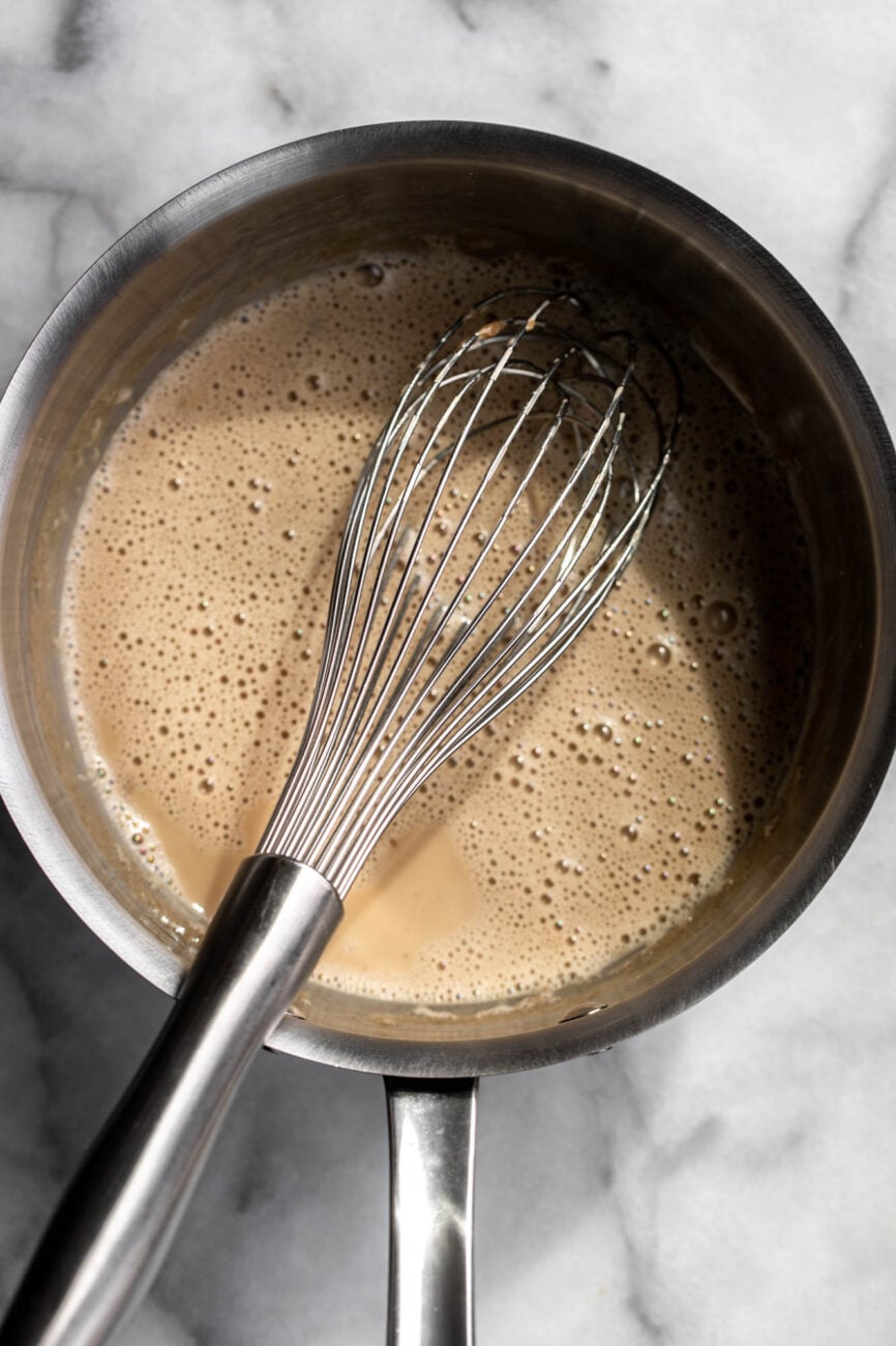 Salted butterscotch mixture in pot with whisk.