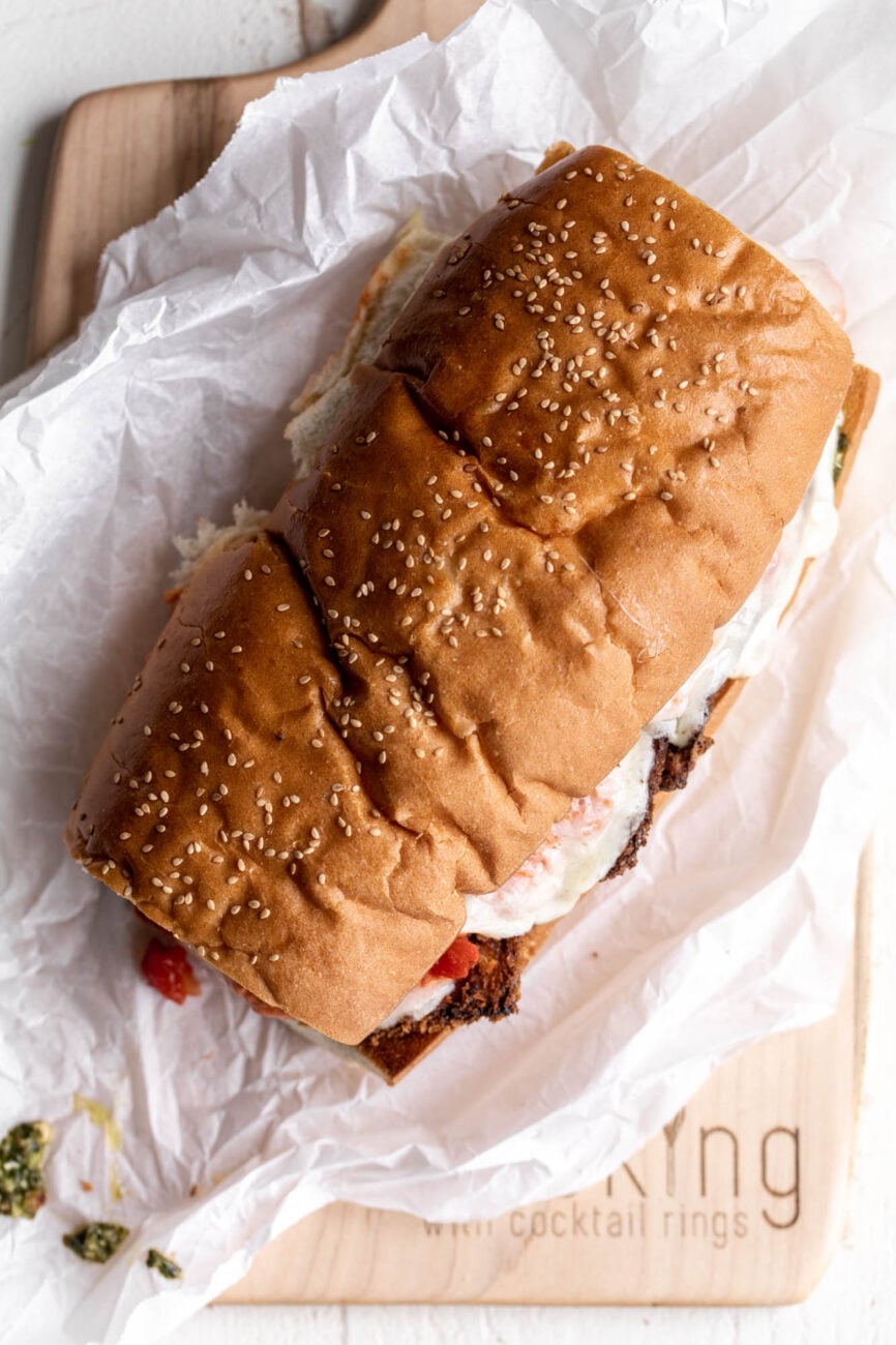 closed eggplant parmesan sandwich on sesame seed sub sandwich roll.