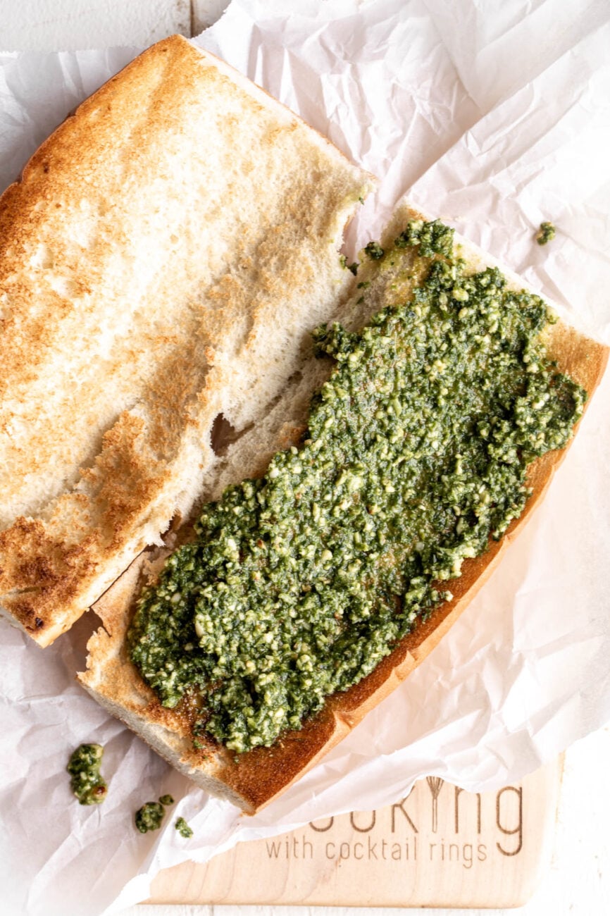 toasted sandwich bread with pesto spread over.