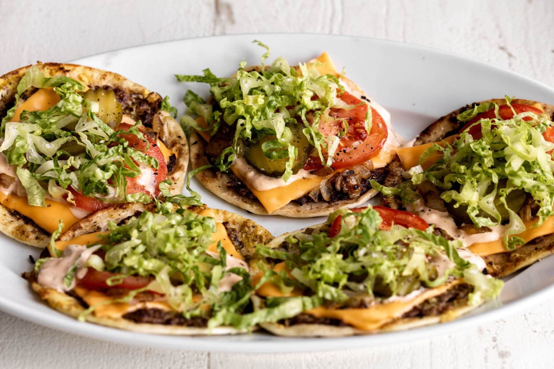 animal style smashburger taco with cheese lettuce tomato and pickles.