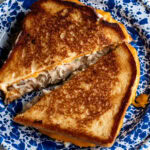 golden brown griddled crab melt on blue enamel plate.
