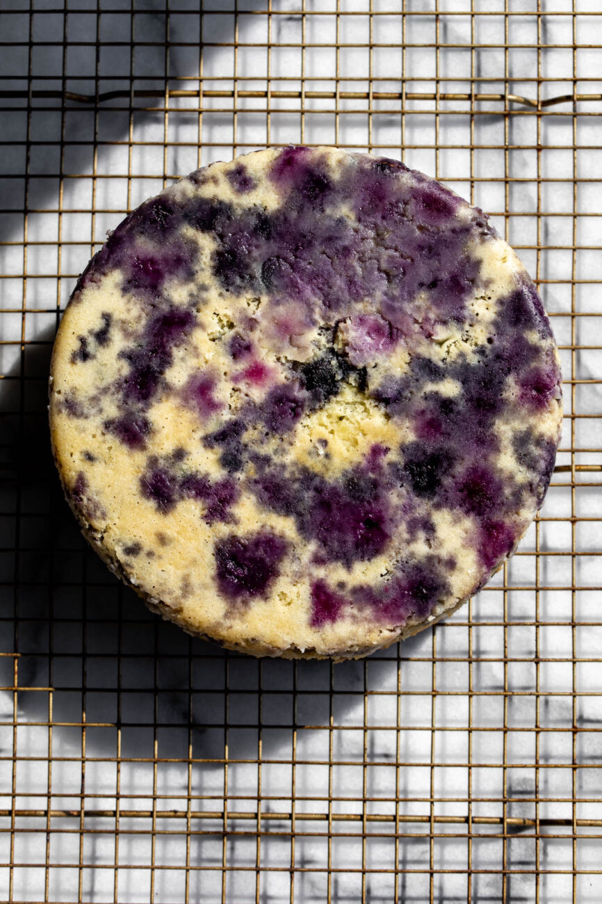 baked lemon blueberry cake turned out onto wire cooling rack.