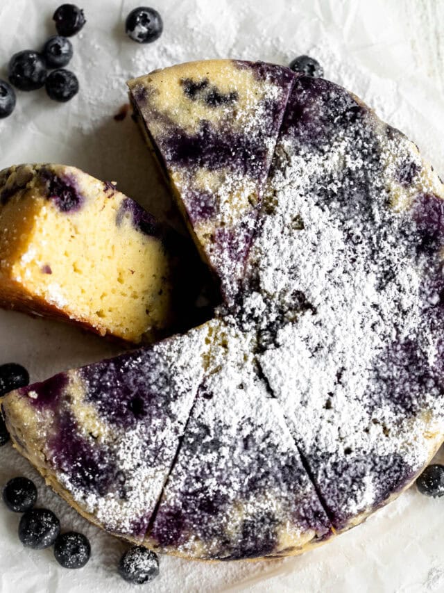 Zesty lemon cake bursting with blueberries is a celebration of summer indulgence. The vibrant flavors in the dense yet moist cake resemble everyone's favorite Starbucks lemon pound cake with the addition of juicy summer blueberries. Whether hosting a backyard barbecue, planning an impromptu picnic, or simply looking to satisfy a sweet tooth, this lemon blueberry cake is the perfect treat to brighten any occasion this summer. Made in a round cake pan (or loaf tin) & garnished with a dusting of powdered sugar.
