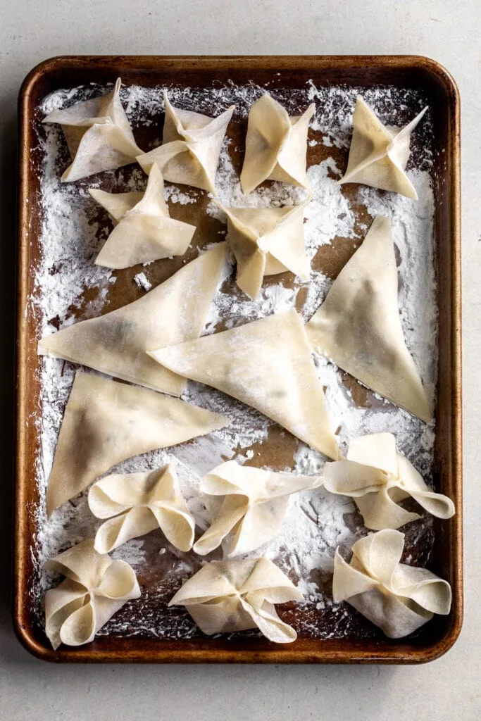 folded crab rangoons on baking sheet.