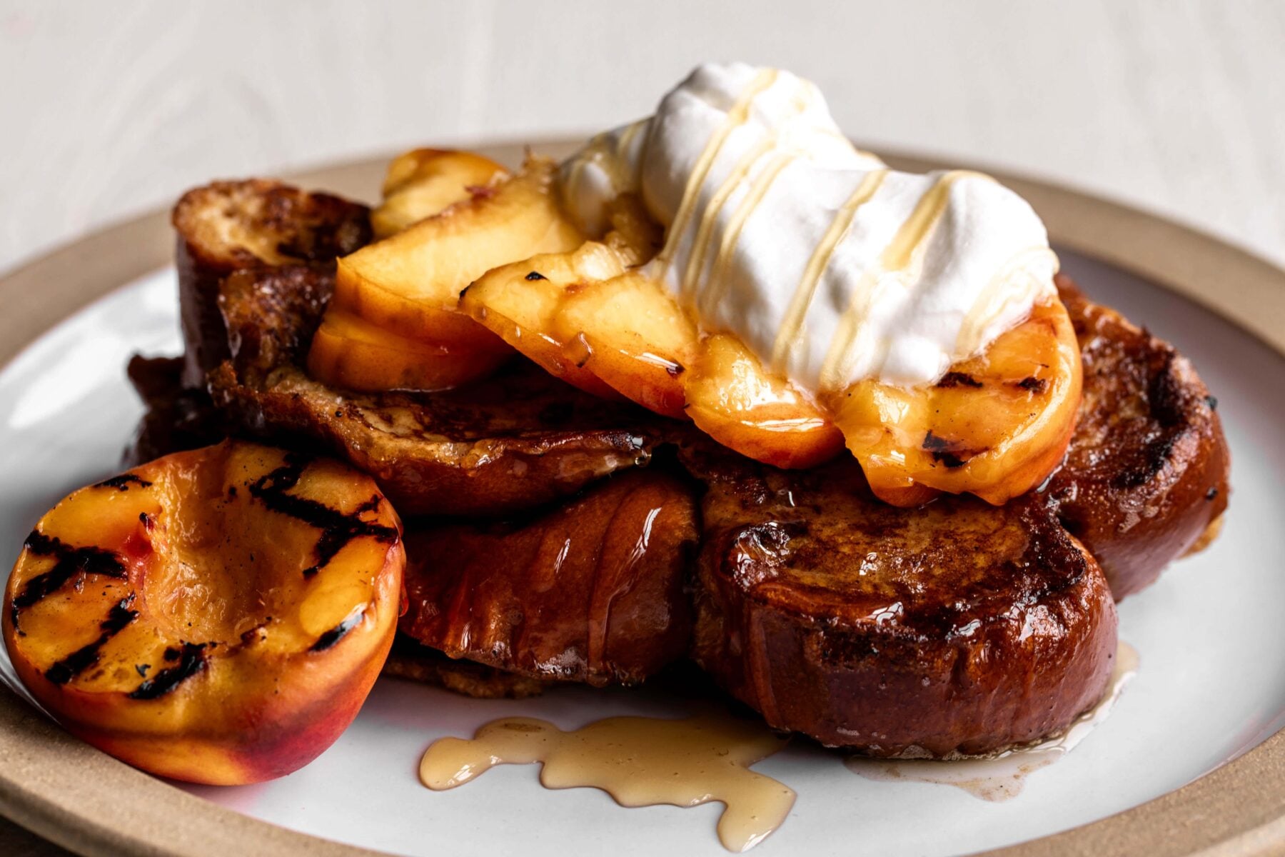 challah french toast with grilled peaches homemade whipped cream and honey.