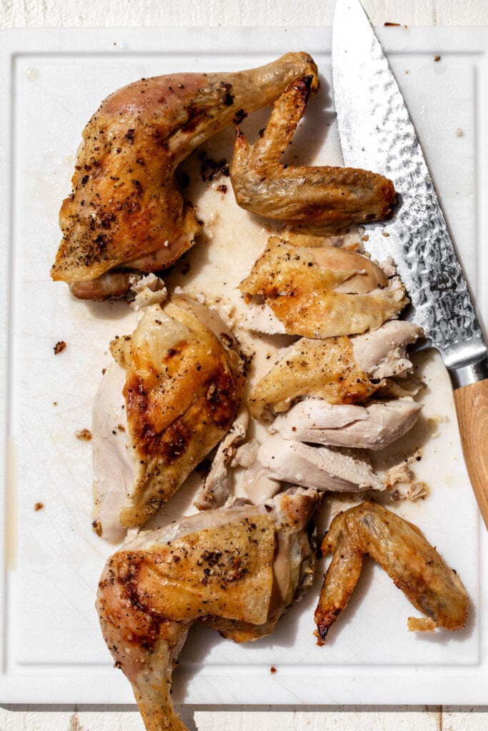 fabricated lemon and garlic roast chicken on cutting board.