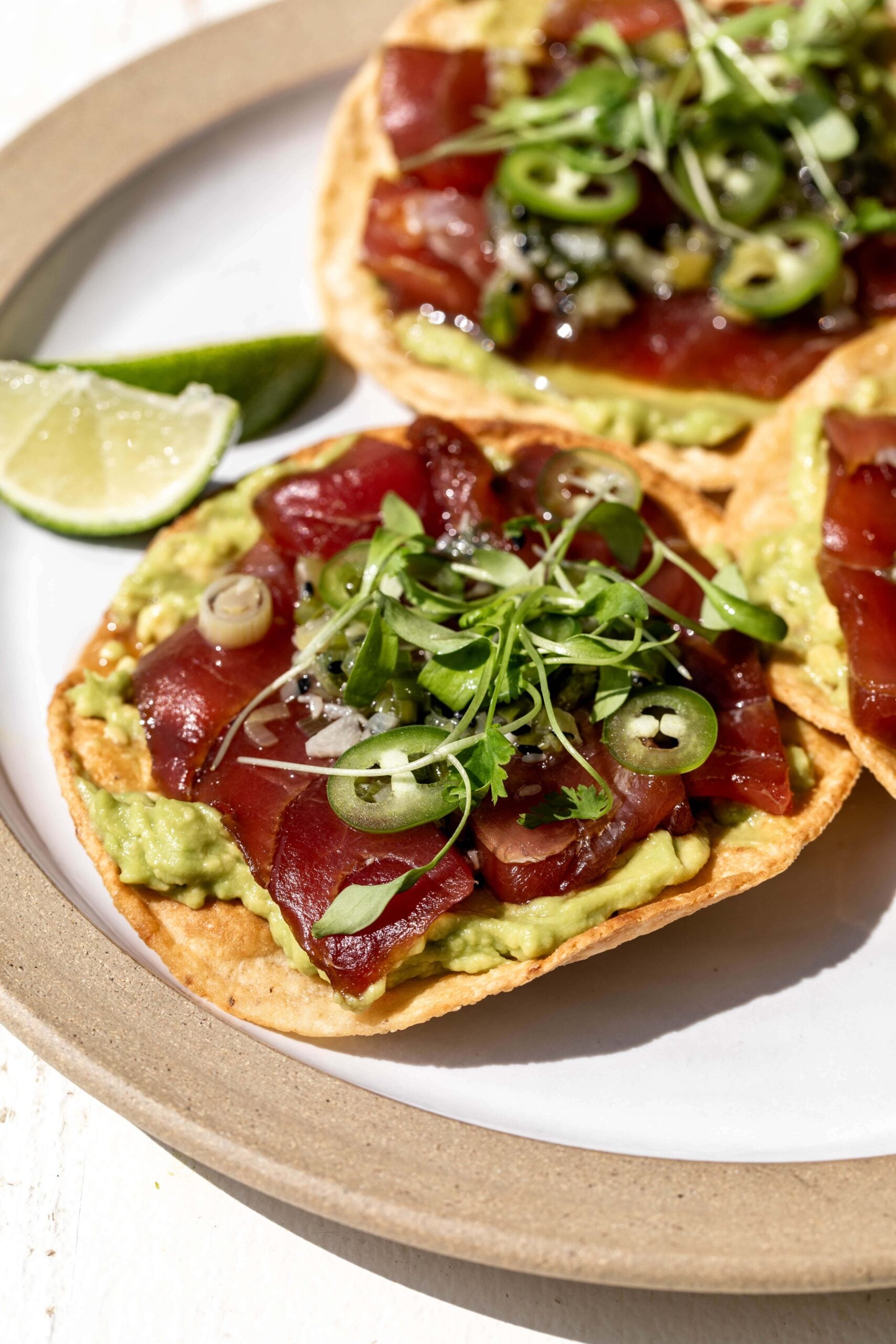 tuna tostada with lime wedges.