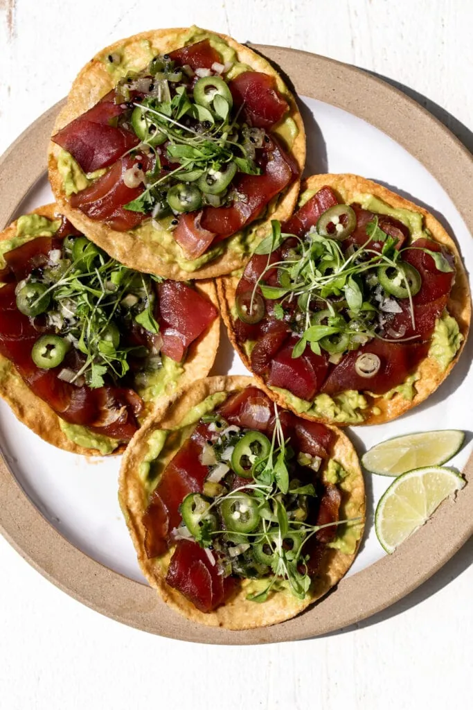 Tostadas with avocado mash and slices of raw tuna.