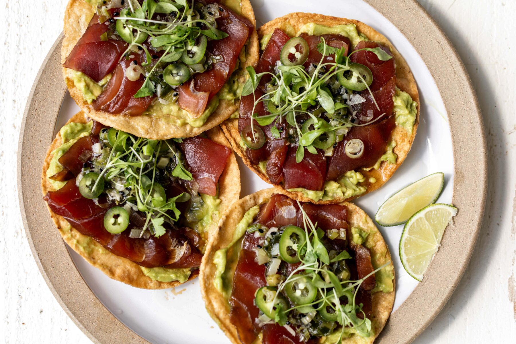 tuna tostada with scallion garlic sauce and serrano slices.