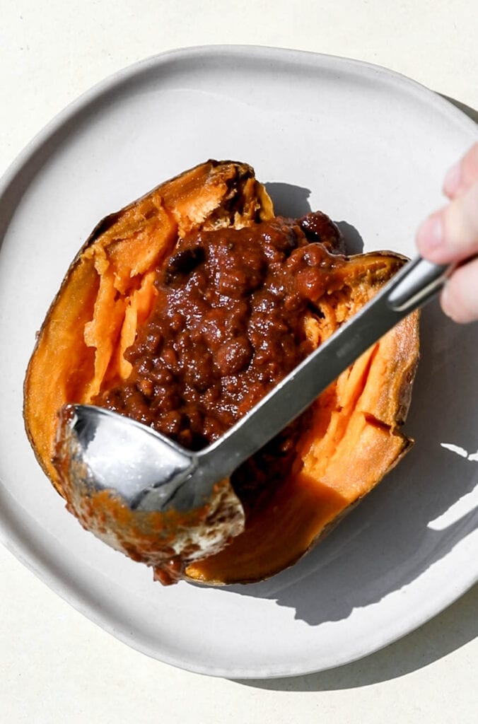 split roasted sweet potato with ladle of classic beef chili