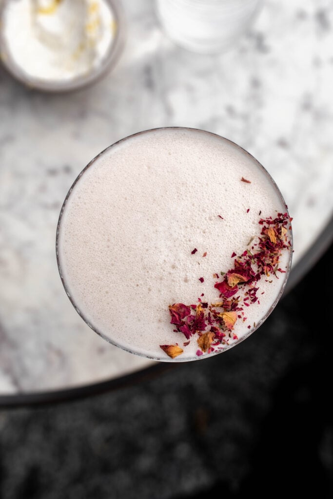 cocktail drink garnished with rose petals.