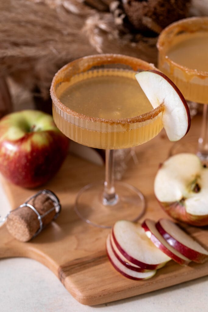 Apple cider mimosa autumn cocktail garnished with apple slices.