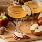 Apple cider mimosa autumn cocktail garnished with apple slices.
