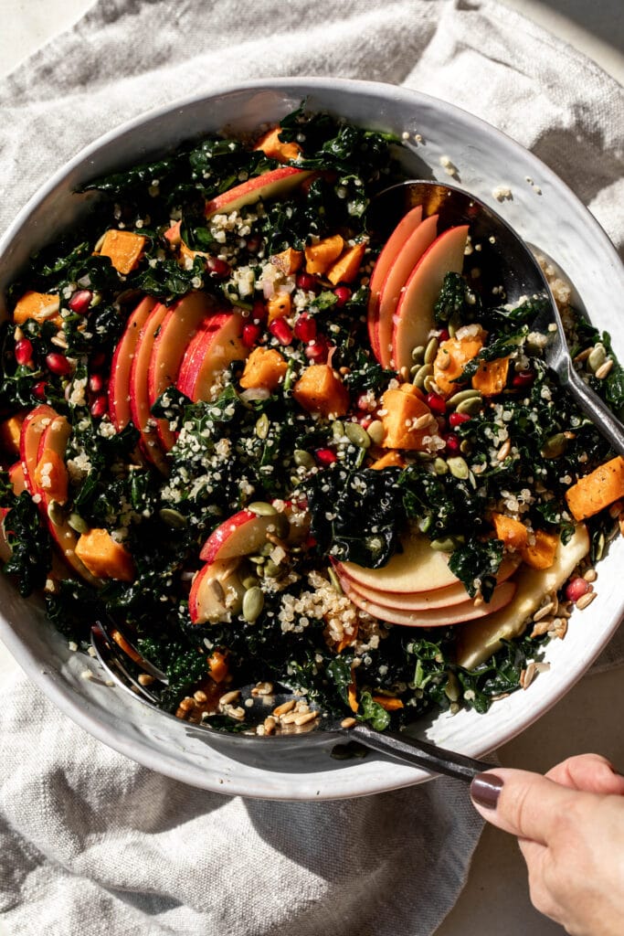 kale harvest grain bowl quinoa with apple slices in white serving bowl.