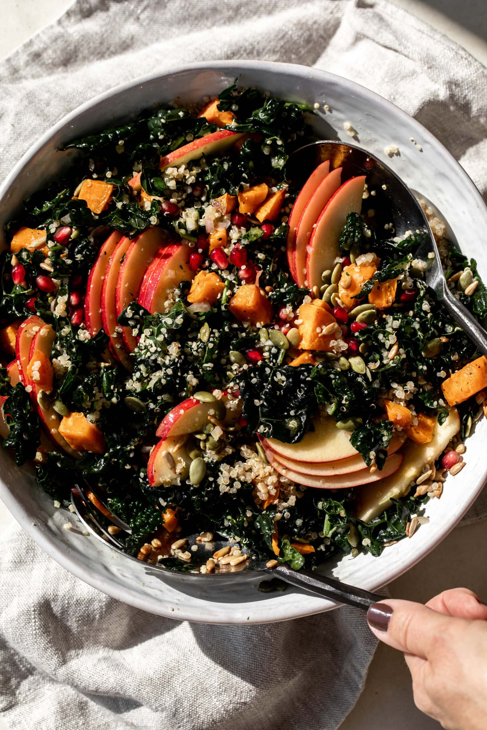 kale harvest grain bowl quinoa with apple slices in white serving bowl.