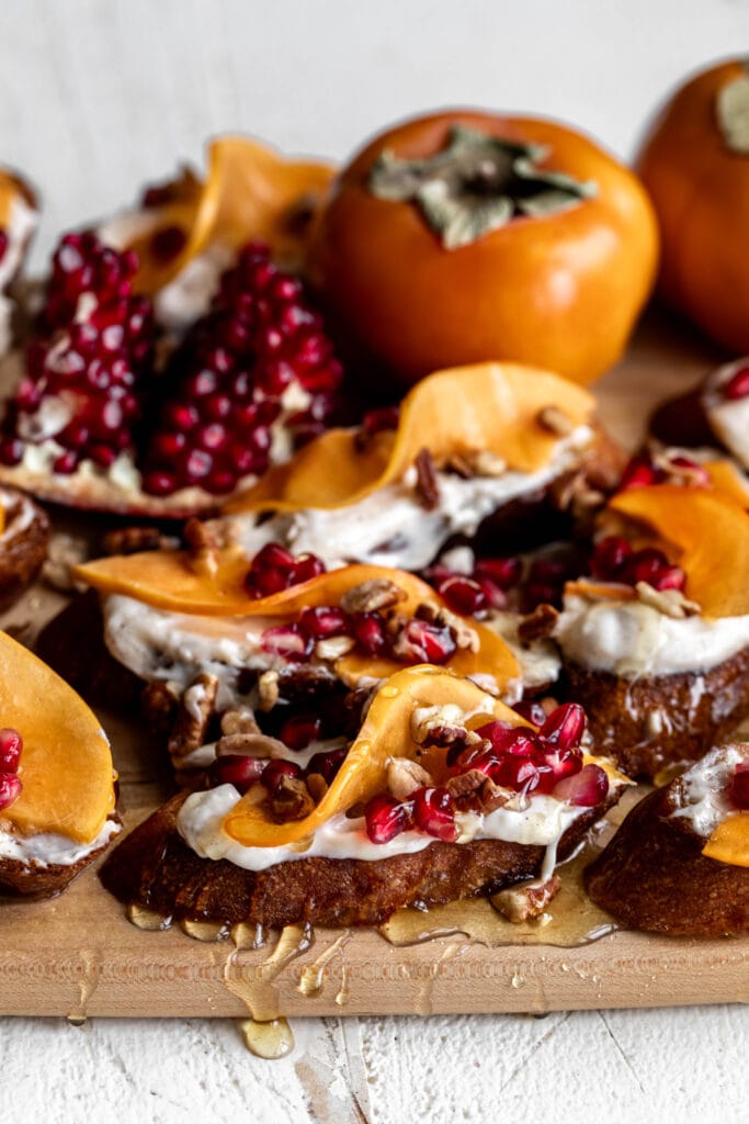toasts topped with spiced cream cheese with persimmon slices and pomegranate seeds.