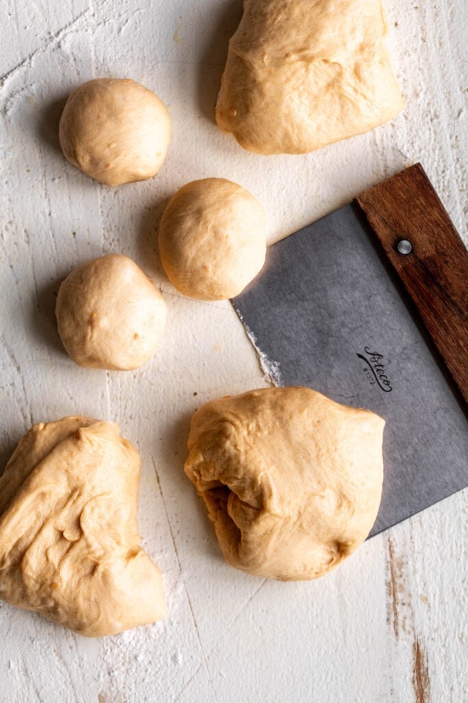 divided sweet potato dinner roll dough with bench scraper.
