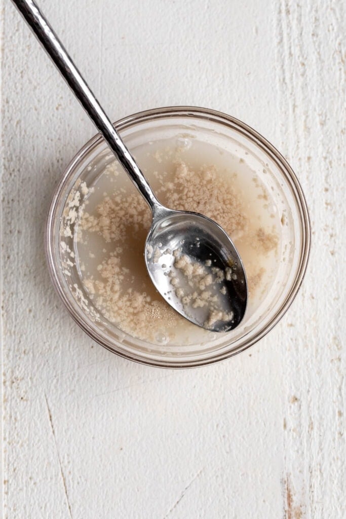 yeast dissolved in water in glass mixing bowl.