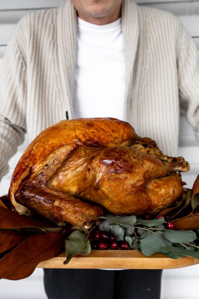 herb brined whole thanksgiving turkey on cutting board.