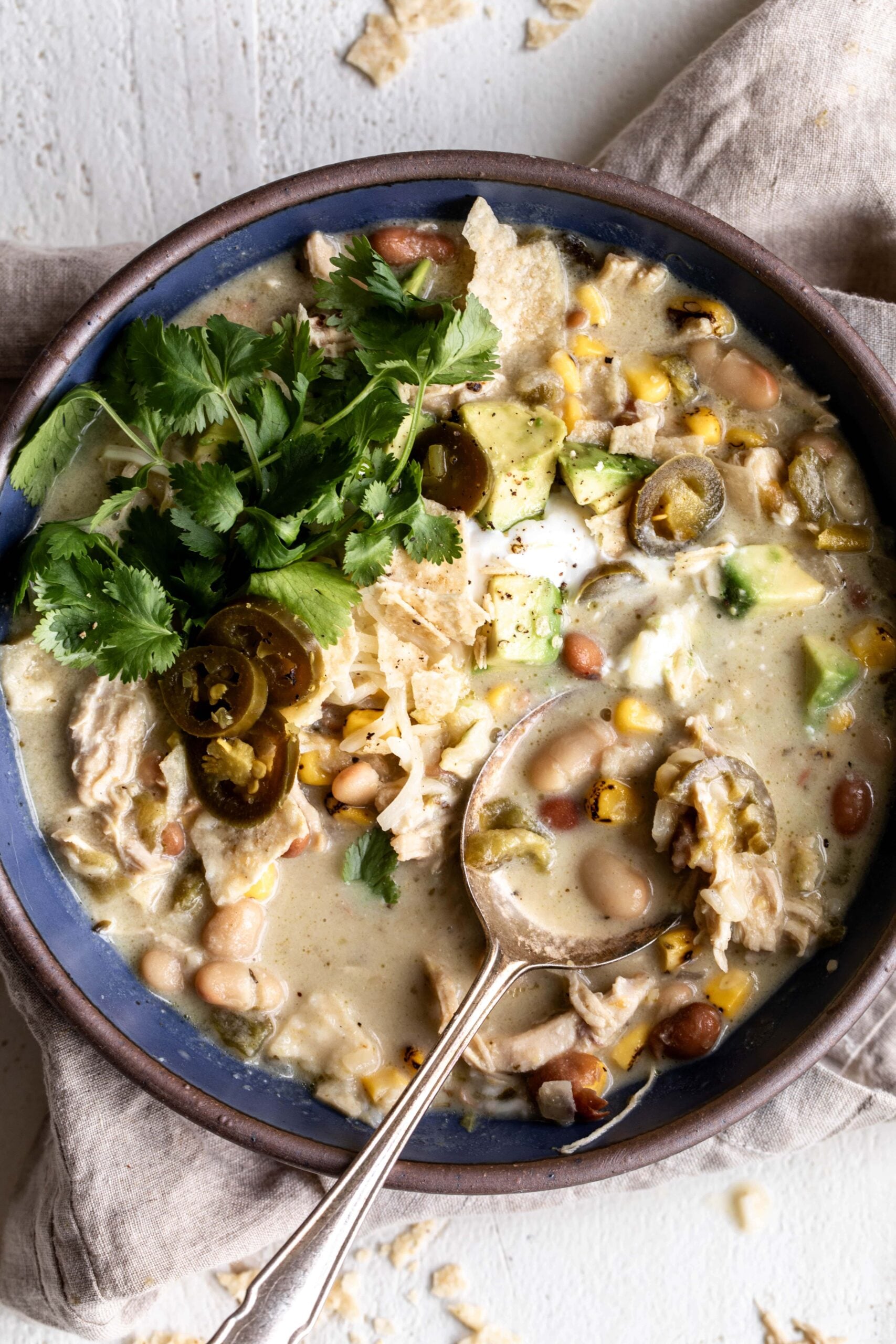 white chicken chili with beans topped with avocado and cilantro.