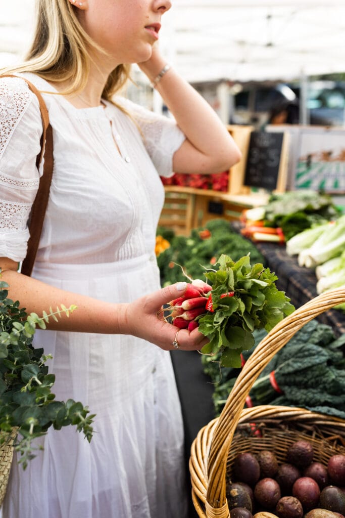 buying radishes at the farmers market with woven basket.
