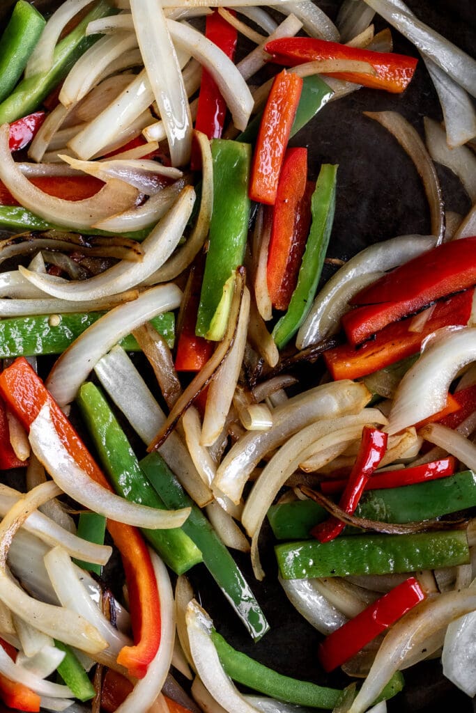 sautéed sliced onions and red and green bell peppers in cast iron pan.