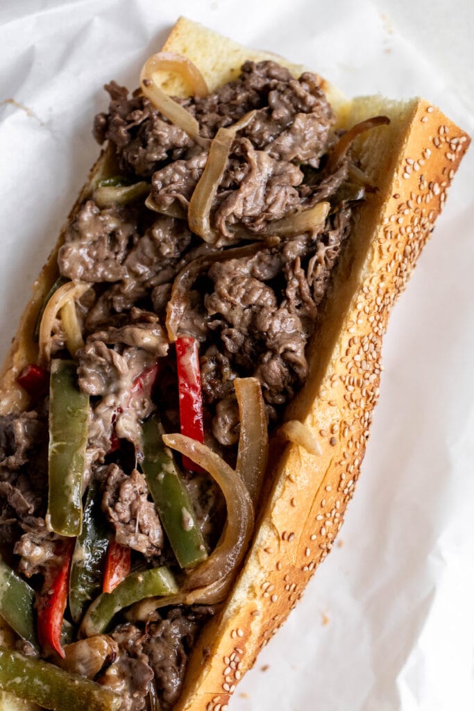 cheesesteak with peppers and onions piled into hoagie roll.