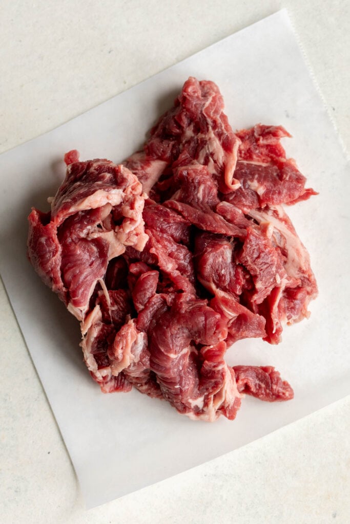 thinly sliced steak portioned out on parchment paper.