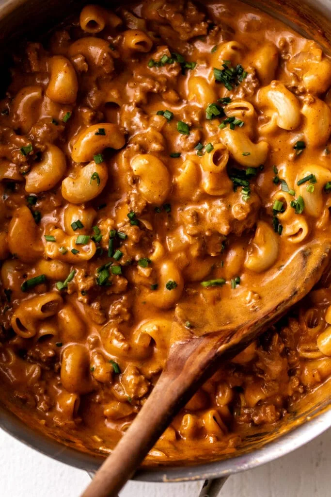 Homemade hamburger helper with ground beef, pasta, and creamy cheese sauce in pot.