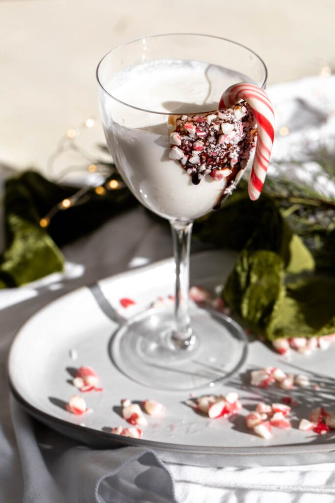 a glass of Peppermint Martini garnished with a mini candy cane.