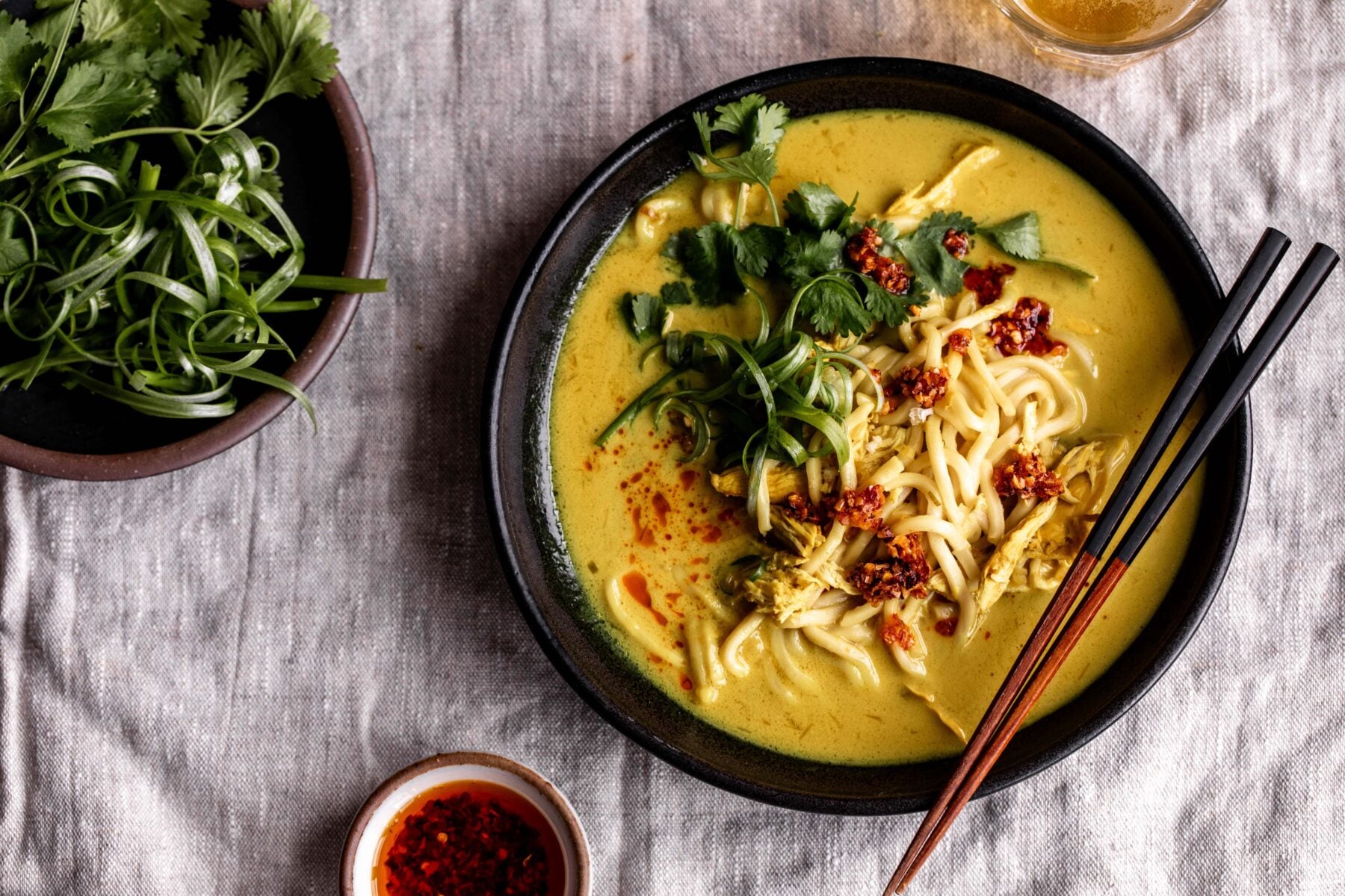 coconut turmeric chicken soup with cilantro and chili crisp with chopsticks.