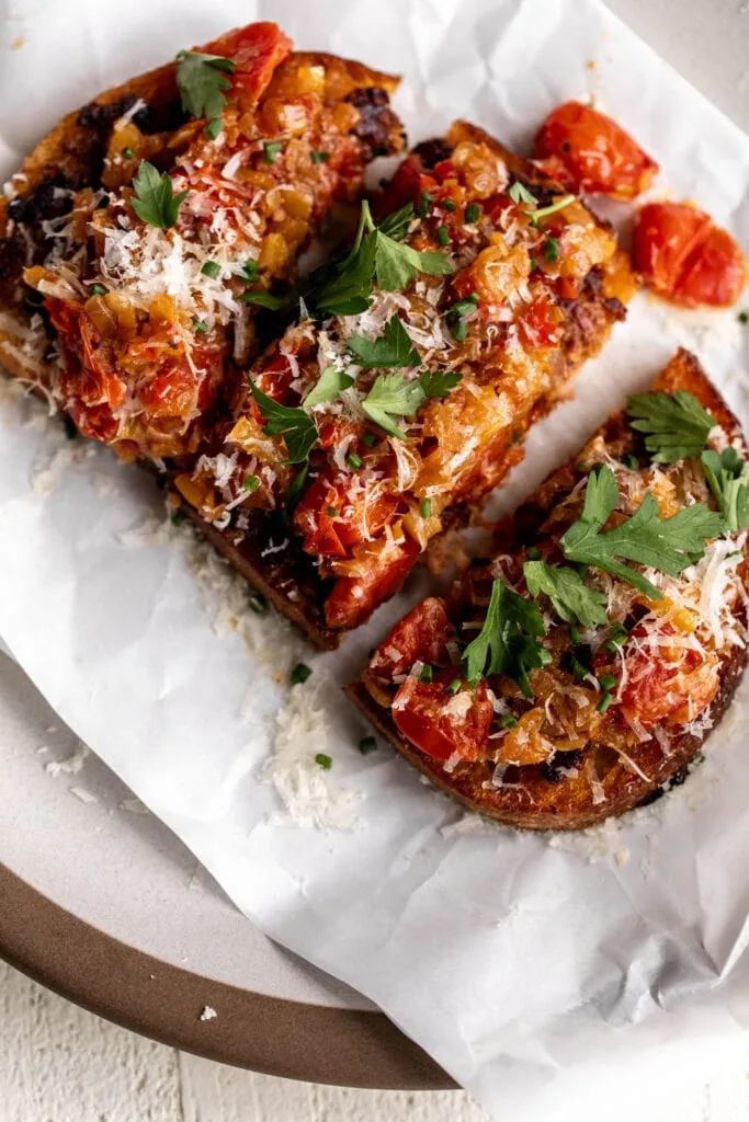 sausage and peppers toasts with parmesan cheese and chopped herbs.