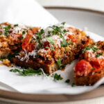 Italian sausage and peppers toast garnished with grated Parmesan and chopped herbs.