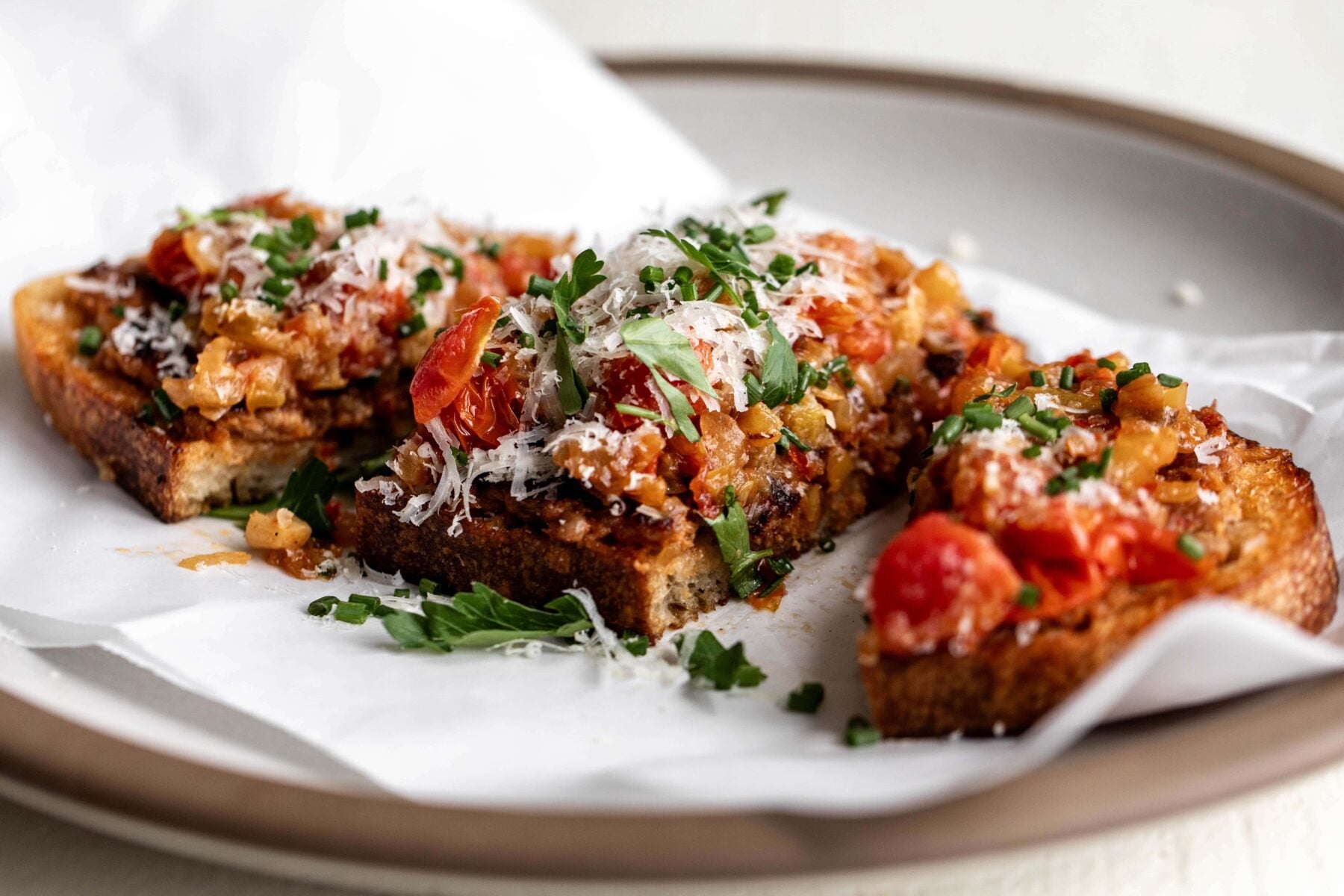 Italian sausage and peppers toast garnished with grated Parmesan and chopped herbs.