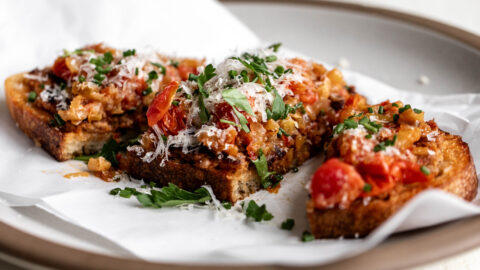 Italian sausage and peppers toast garnished with grated Parmesan and chopped herbs.
