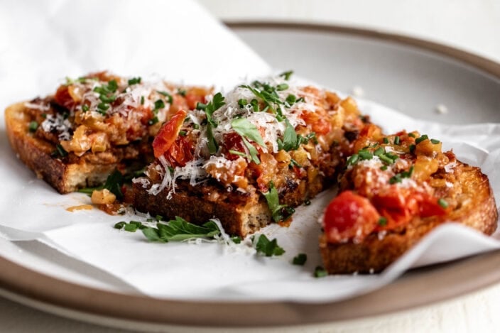 Italian sausage and peppers toast garnished with grated Parmesan and chopped herbs.