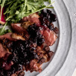 sliced seared duck breast with blueberry pan sauce.