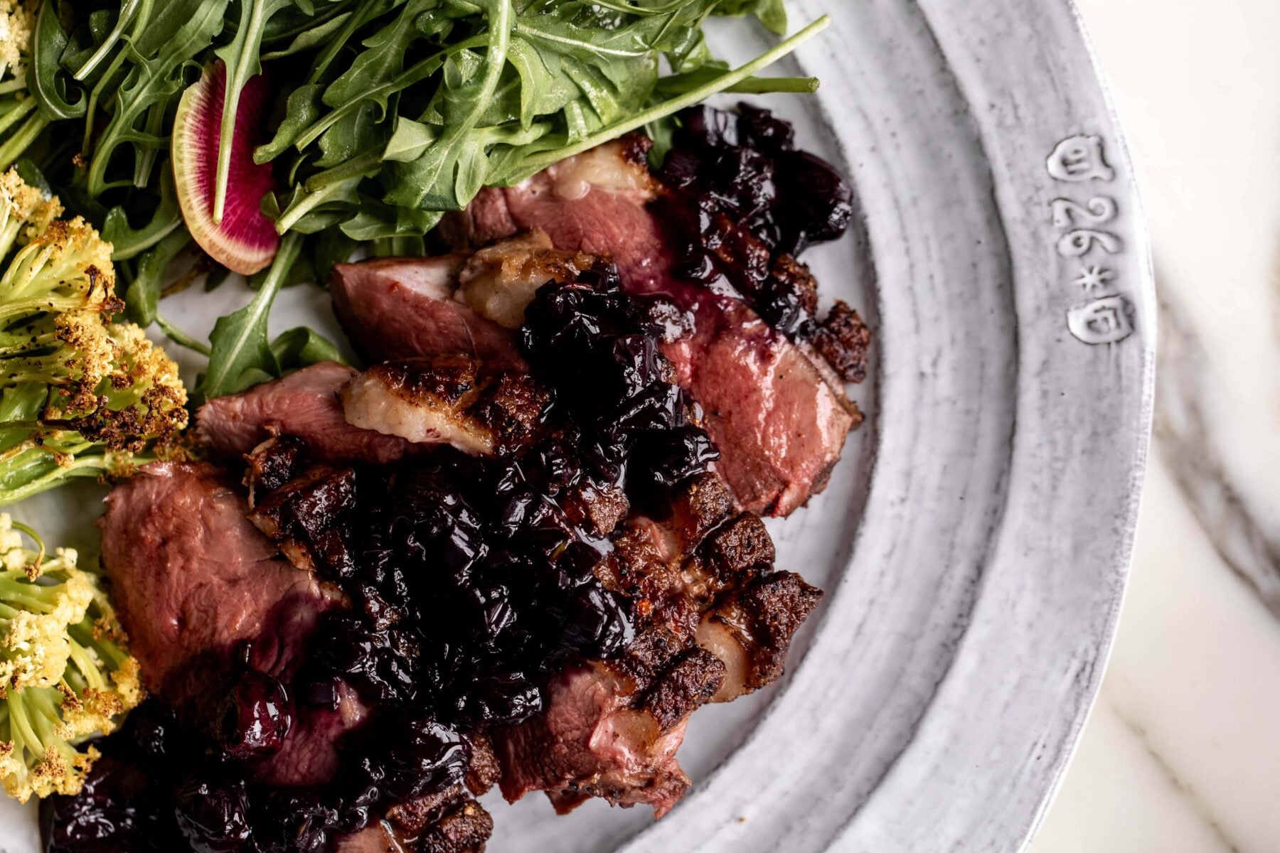 sliced seared duck breast with blueberry pan sauce.