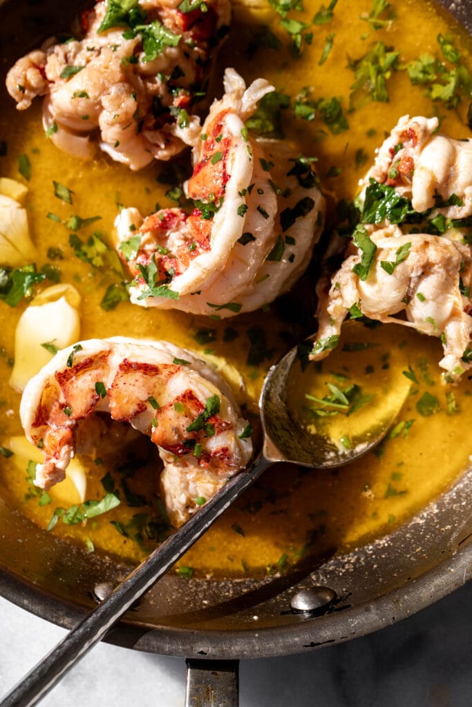 butter poached lobster tails with spoon.