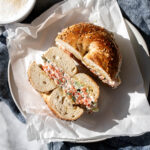 chopped salmon bagel halved on plate with coffee.