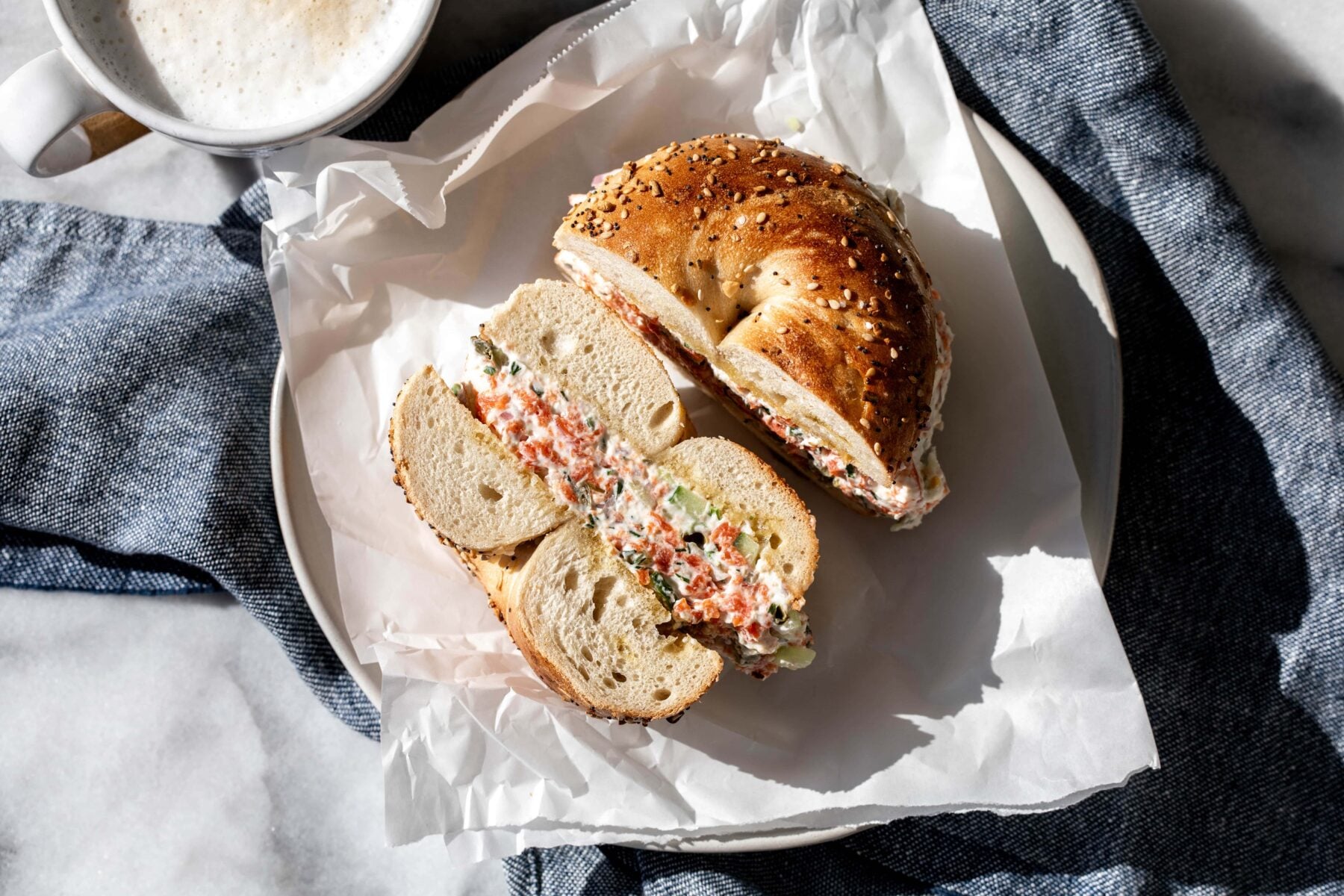 chopped salmon bagel halved on plate with coffee.