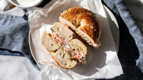 chopped salmon bagel halved on plate with coffee.