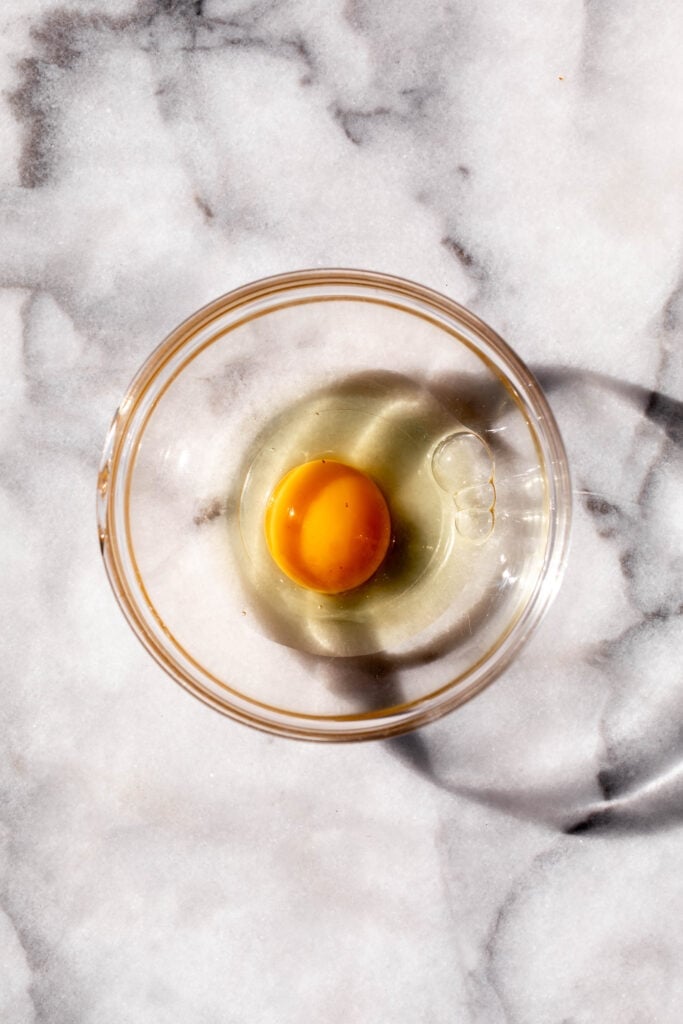 cracked egg in glass ramekin.