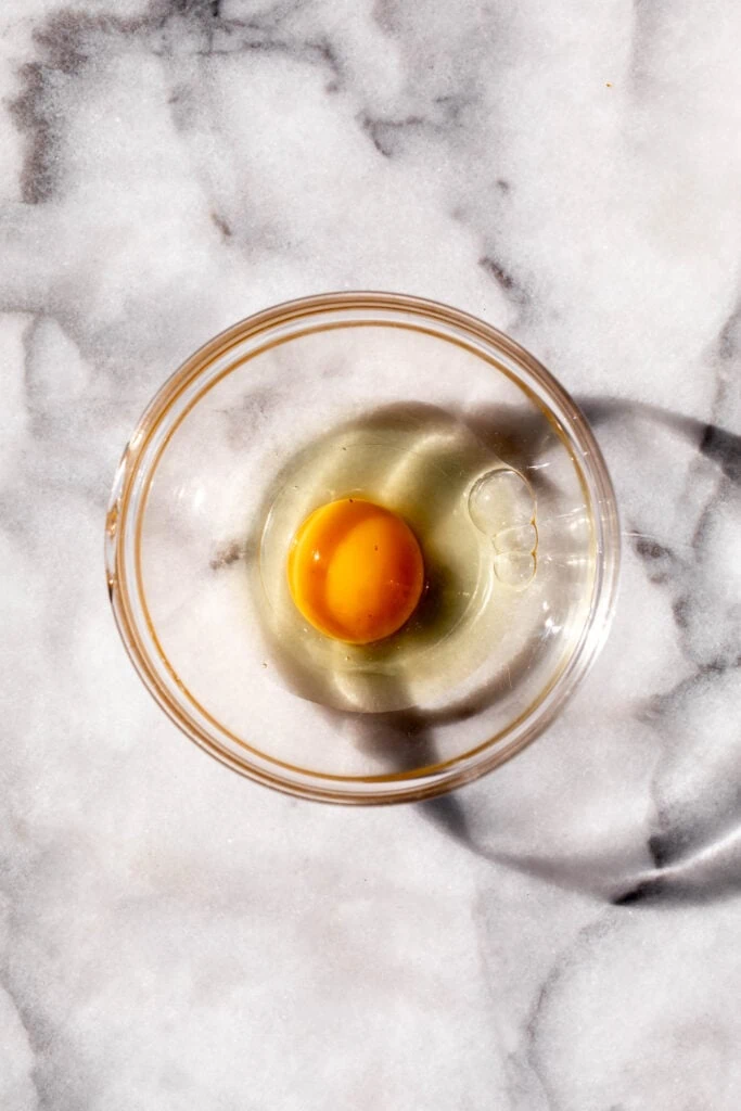 cracked egg in glass ramekin