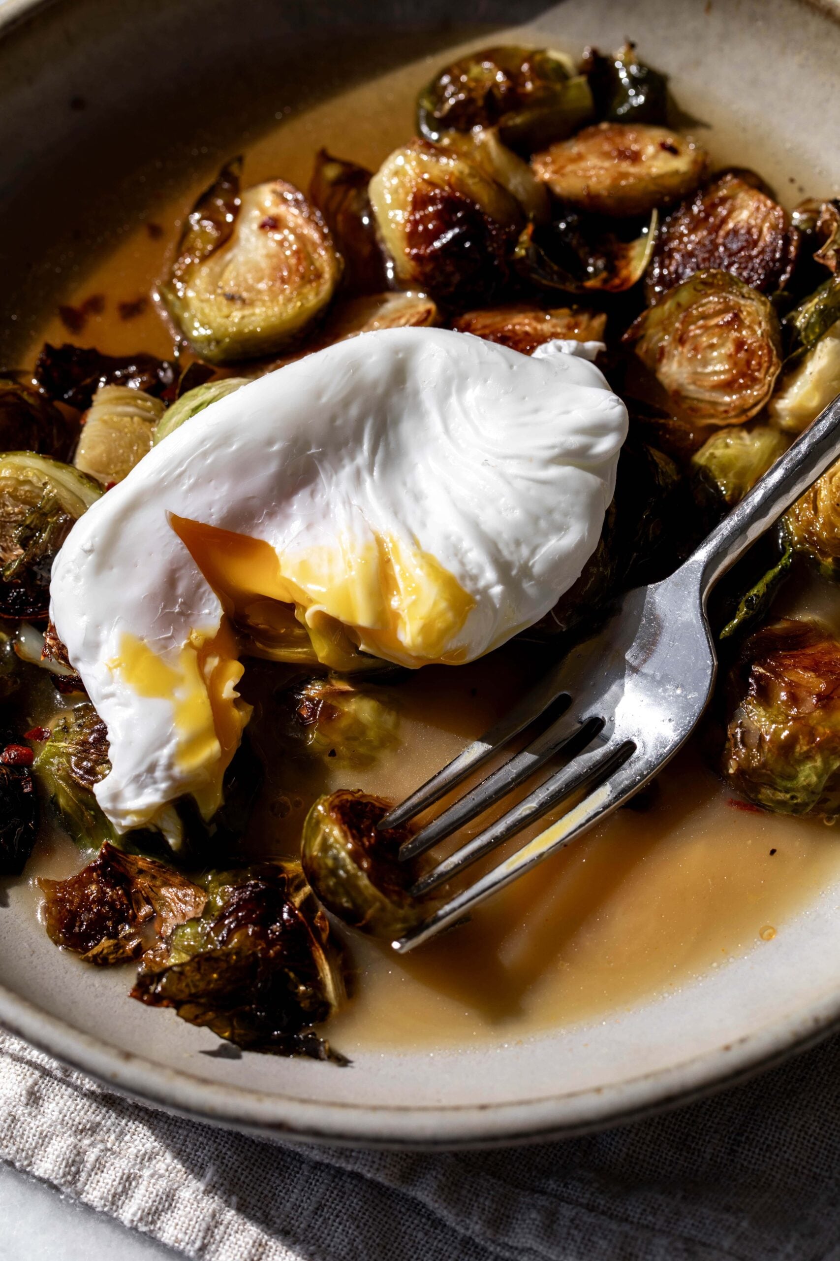 roasted brussels sprouts in a light bacon dashi broth with a poached egg split open.