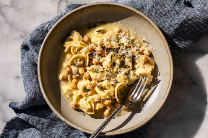 easy rosemary and chickpea tortellini pasta with chopped rosemary and Parmesan cheese.