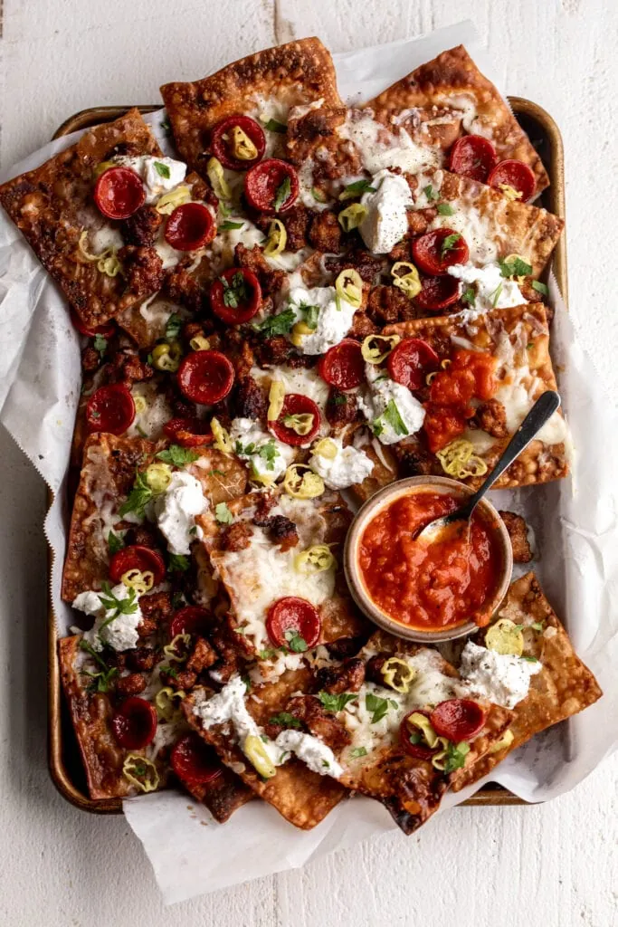 assembled Italian Nachos on baking sheet with pepperoni and pepperoncini.