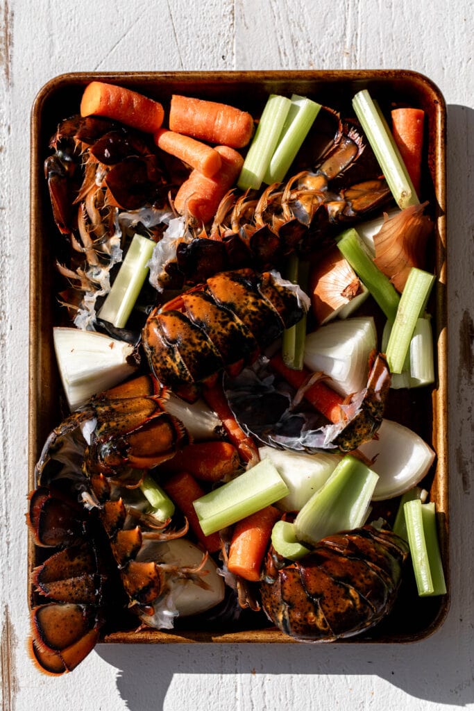 lobster shells, carrots, celery and onion on baking sheet