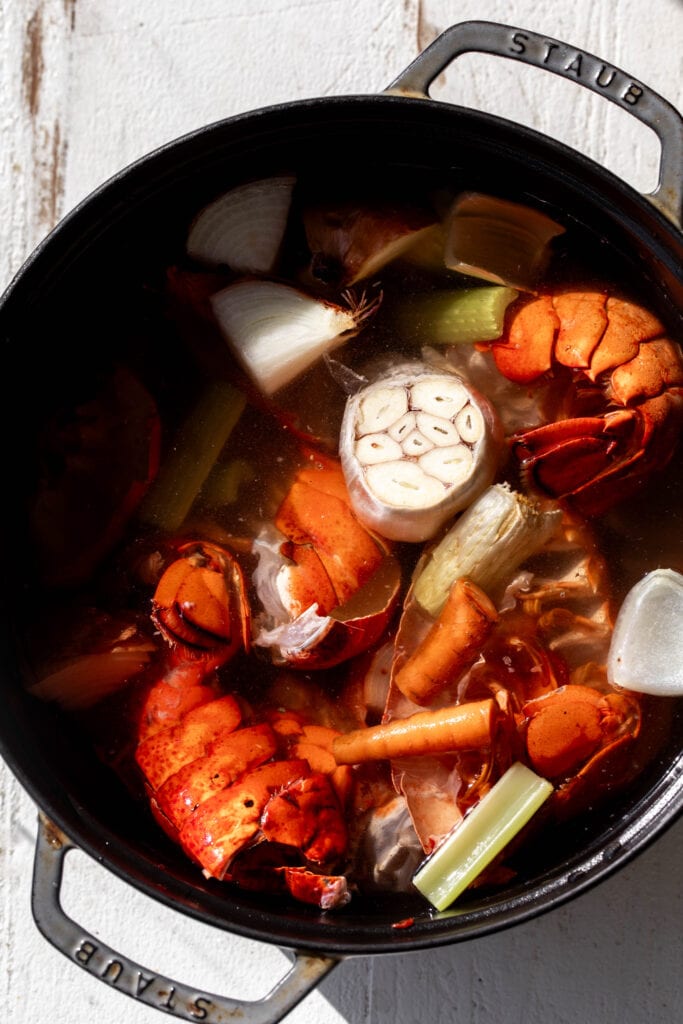 homemade seafood stock in pot lobster tails, garlic, onions, celery and carrots.
