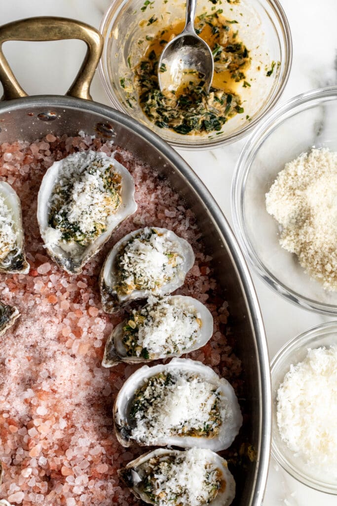 shucked oysters arranged on pink himalayan salt with greens, panko breadcrumbs and cheese.